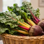 Bunches of rainbow chard and beetroot stacked in a wicker basket under warm shop lighting